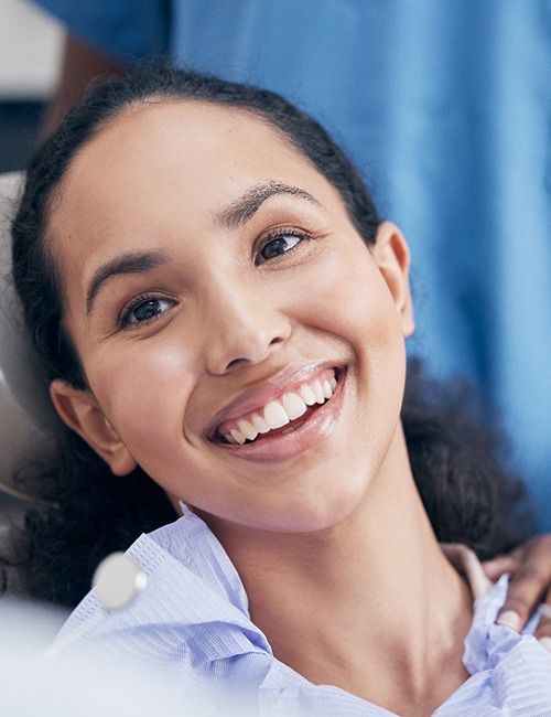 Woman smiling at dentist while sitting in treatment chair