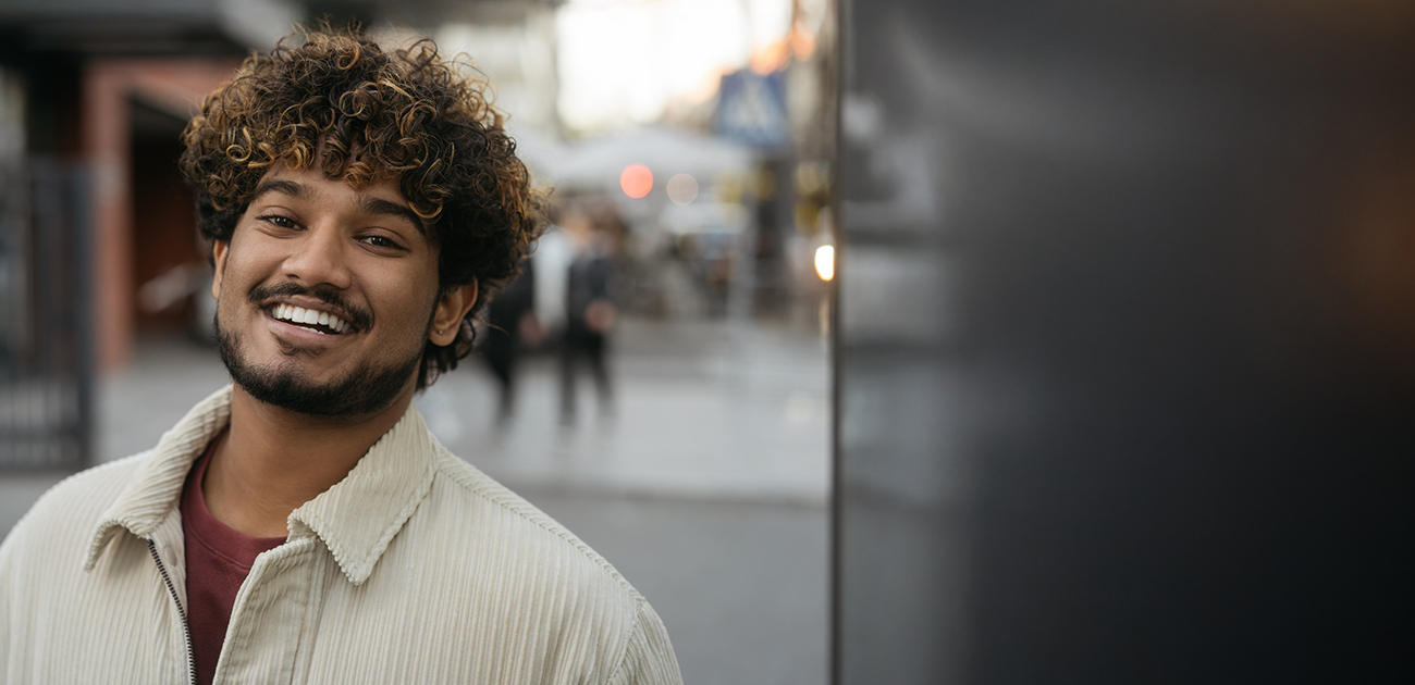 Bearded man in collared jacket walking down street smiling